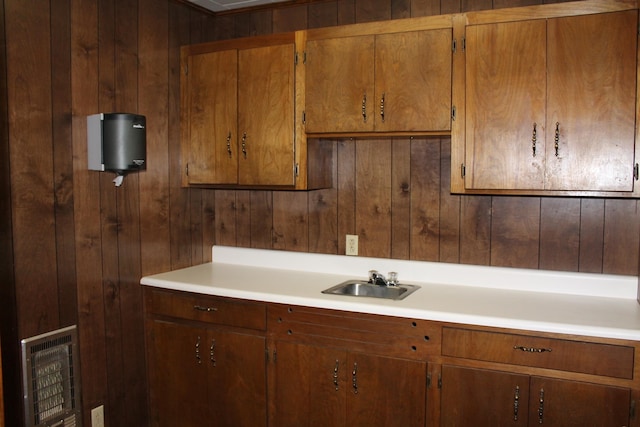 kitchen featuring sink, heating unit, and wood walls