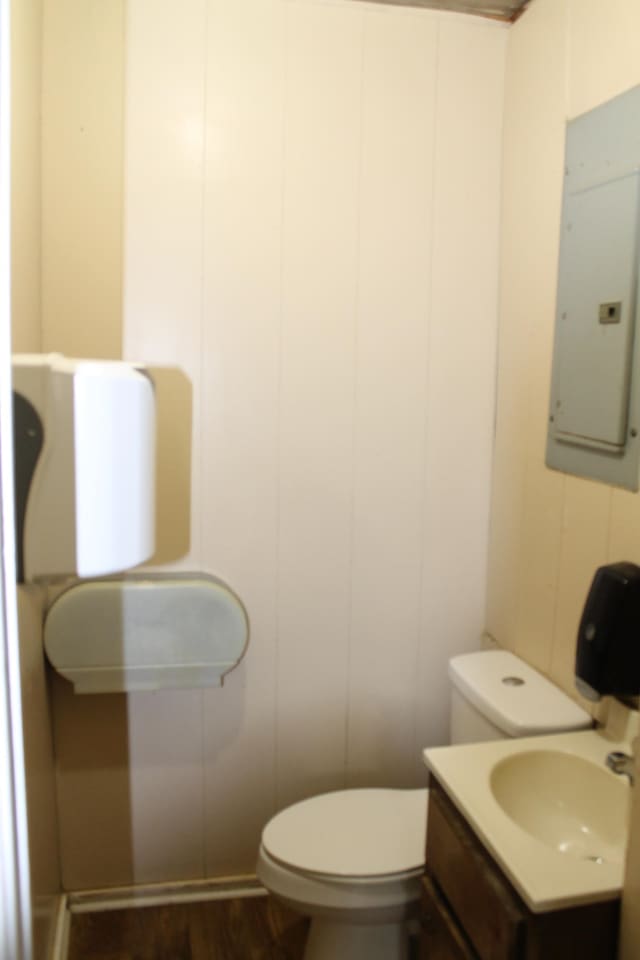 bathroom with toilet, wood-type flooring, sink, and electric panel