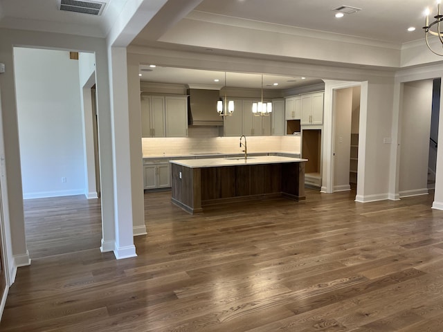 kitchen featuring decorative light fixtures, sink, dark hardwood / wood-style flooring, decorative backsplash, and a kitchen island with sink