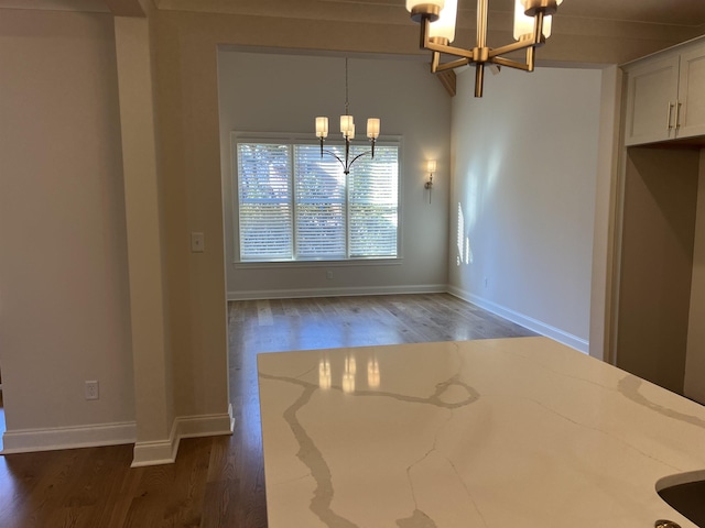 unfurnished dining area featuring lofted ceiling, dark hardwood / wood-style flooring, and a chandelier