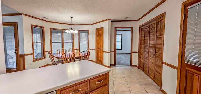 kitchen featuring ornamental molding, a textured ceiling, light tile patterned floors, decorative light fixtures, and a notable chandelier