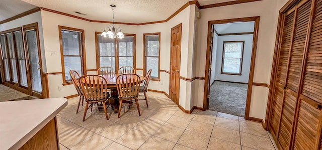 dining space with light tile patterned flooring, ornamental molding, a textured ceiling, and a notable chandelier