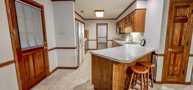 kitchen with kitchen peninsula, a textured ceiling, sink, light tile patterned floors, and white fridge with ice dispenser