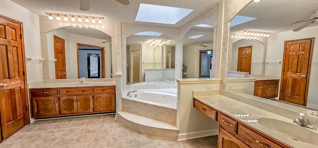 bathroom featuring a skylight, a washtub, vanity, a textured ceiling, and ceiling fan