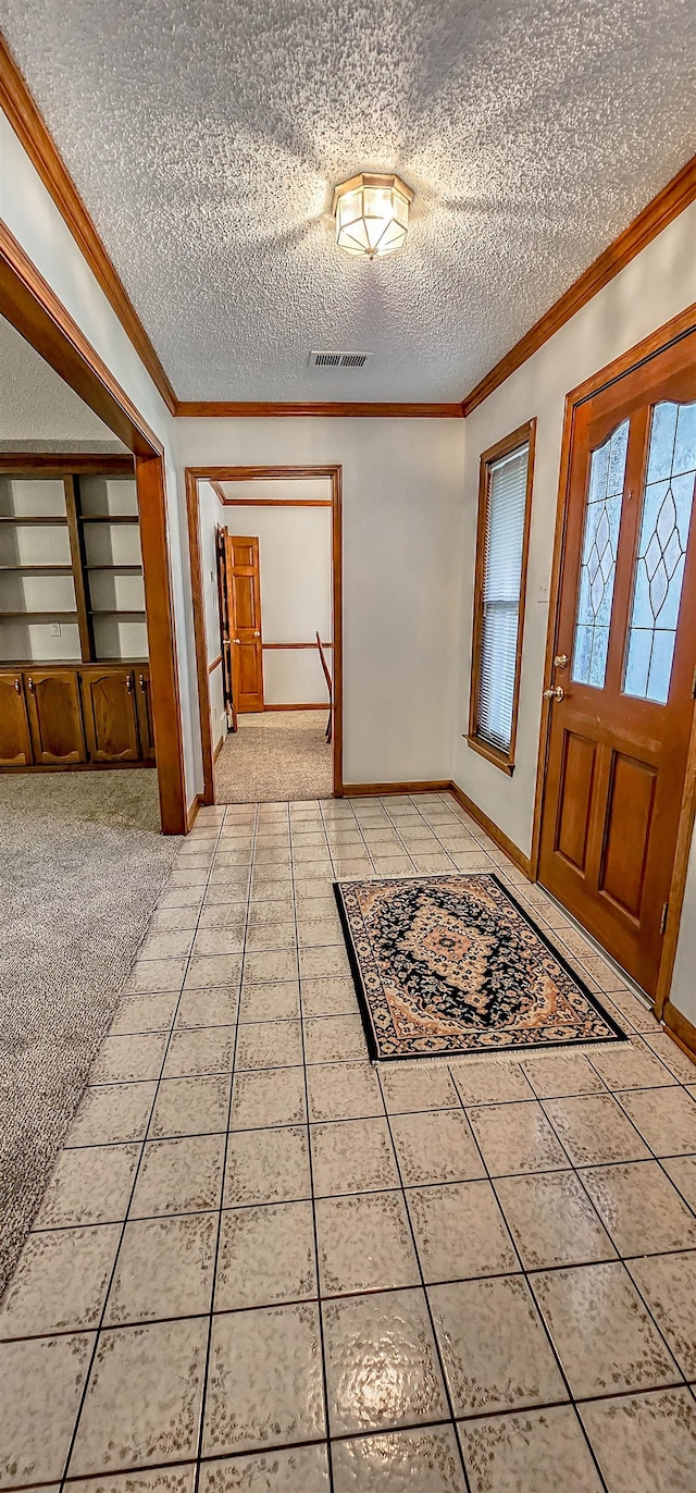 entryway with a textured ceiling, tile patterned floors, and crown molding