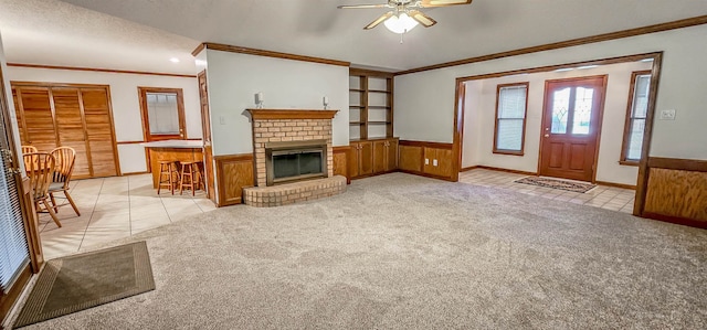 unfurnished living room with wooden walls, ceiling fan, light colored carpet, and a brick fireplace