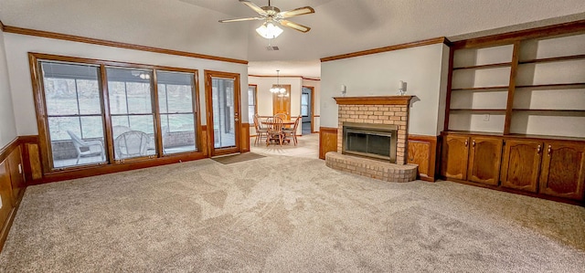 living room with wood walls, light carpet, ceiling fan with notable chandelier, crown molding, and a fireplace