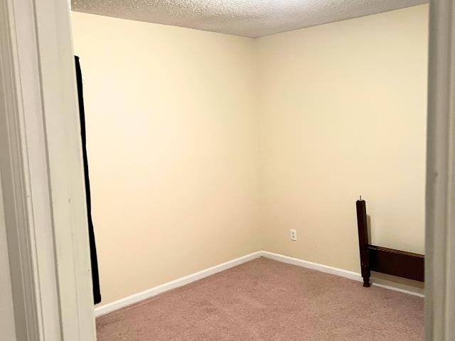 carpeted empty room featuring a textured ceiling