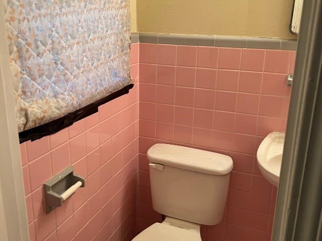 bathroom featuring tile walls and toilet