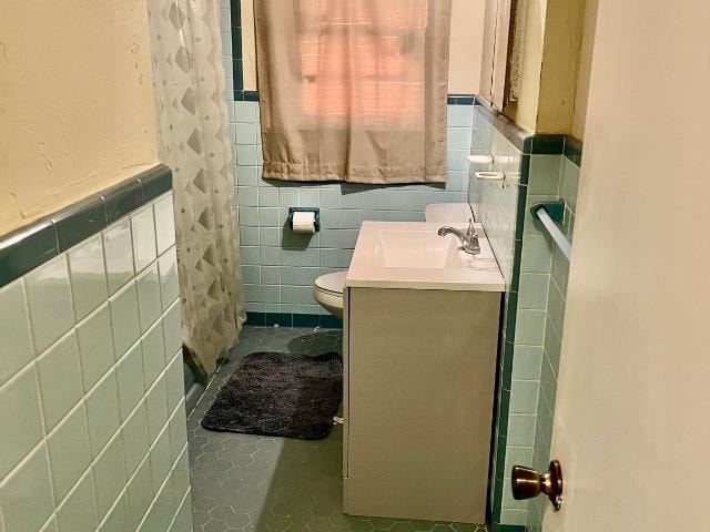 bathroom with vanity, tile walls, and toilet