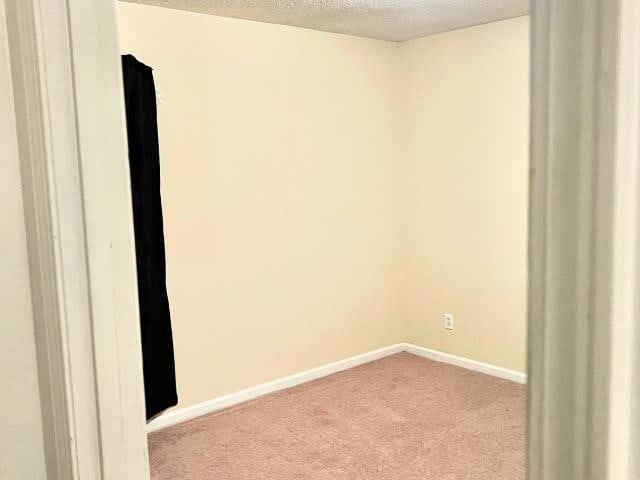 empty room with a textured ceiling and light carpet