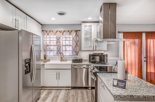 kitchen featuring island exhaust hood, appliances with stainless steel finishes, light hardwood / wood-style floors, and white cabinetry