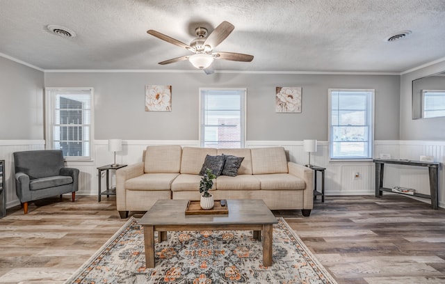 living room with hardwood / wood-style floors, a textured ceiling, and ornamental molding