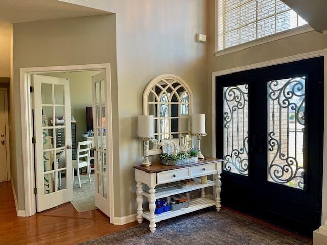 entryway with wood-type flooring, a towering ceiling, and french doors