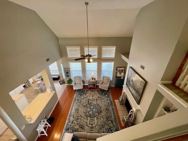 living room with wood-type flooring, high vaulted ceiling, and ceiling fan