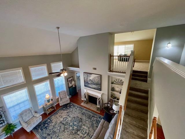 living room with ceiling fan, hardwood / wood-style floors, and vaulted ceiling