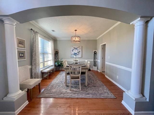 dining room with hardwood / wood-style flooring, a notable chandelier, and crown molding