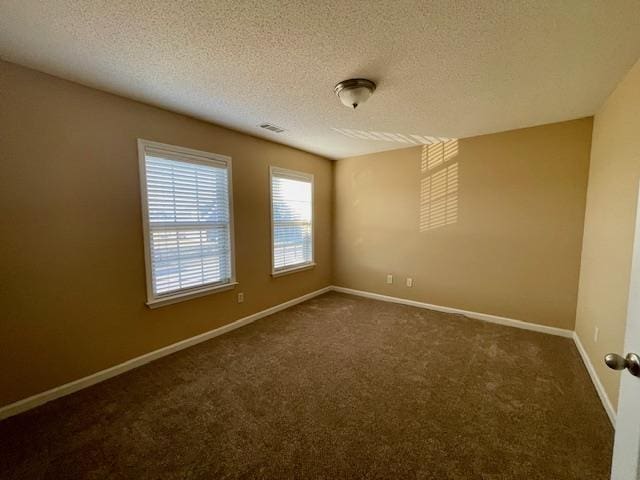 unfurnished room featuring dark carpet and a textured ceiling