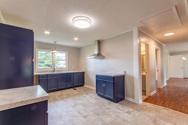 kitchen featuring wall chimney exhaust hood, crown molding, sink, decorative light fixtures, and light hardwood / wood-style flooring