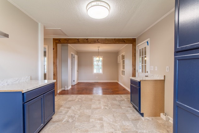 kitchen with ornamental molding, a textured ceiling, blue cabinets, light hardwood / wood-style flooring, and an inviting chandelier