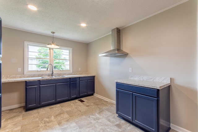 kitchen with crown molding, sink, wall chimney exhaust hood, blue cabinetry, and decorative light fixtures