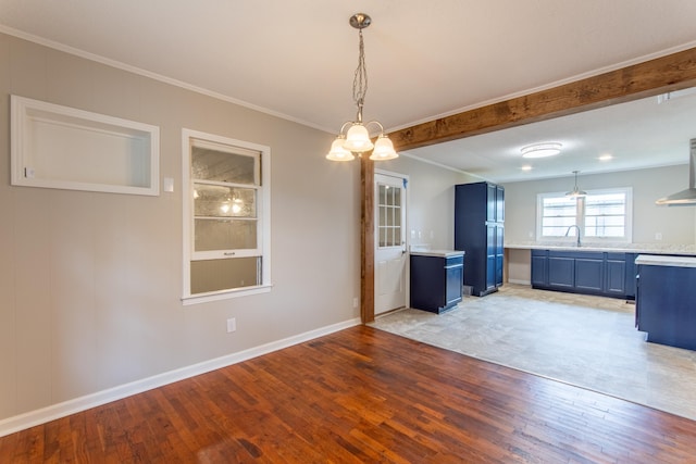 unfurnished dining area with beam ceiling, light hardwood / wood-style flooring, ornamental molding, and sink