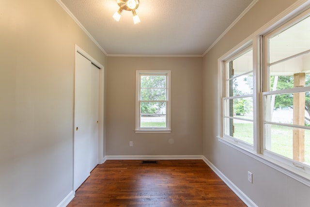 empty room with ornamental molding, a textured ceiling, and dark wood-type flooring