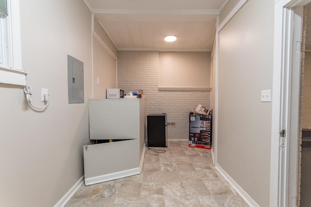 clothes washing area with electric panel, crown molding, and brick wall