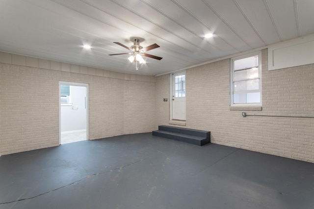 basement with ceiling fan and brick wall