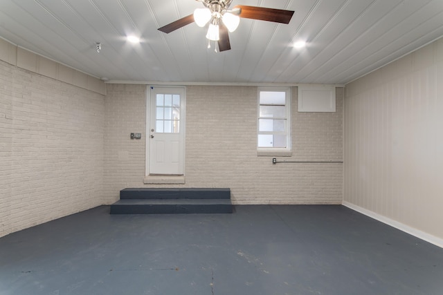 basement featuring ceiling fan and brick wall