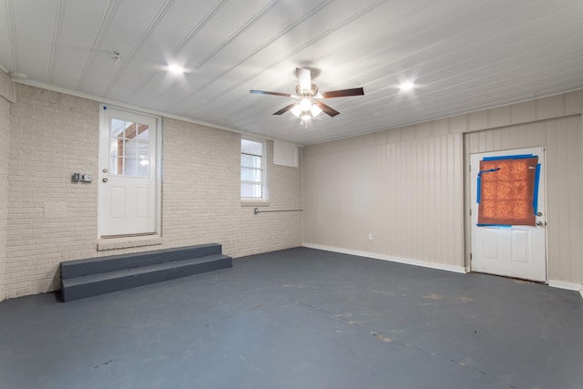 interior space with ceiling fan and brick wall