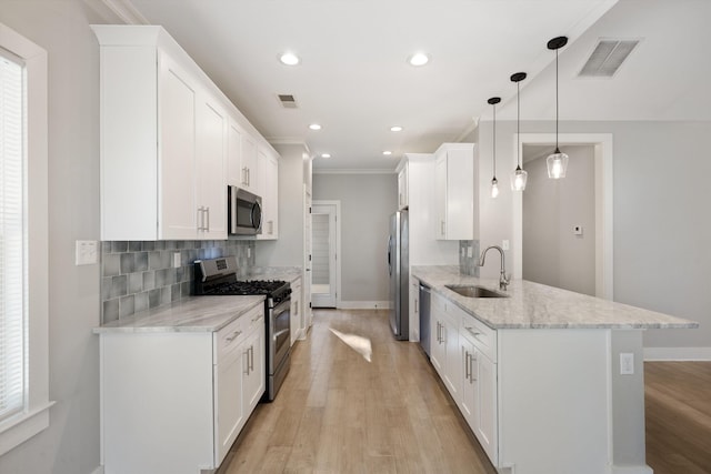 kitchen featuring appliances with stainless steel finishes, sink, decorative light fixtures, light hardwood / wood-style flooring, and white cabinets