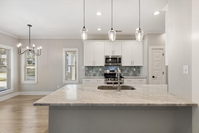 kitchen with crown molding, hanging light fixtures, light stone countertops, white cabinetry, and stainless steel appliances