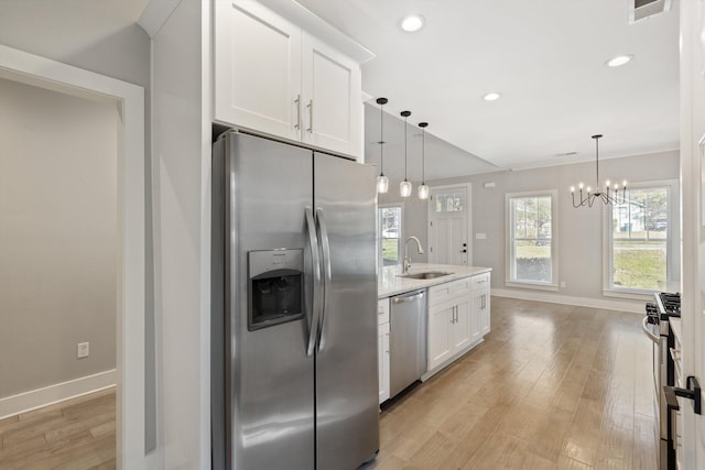 kitchen with hanging light fixtures, light wood-type flooring, sink, and appliances with stainless steel finishes