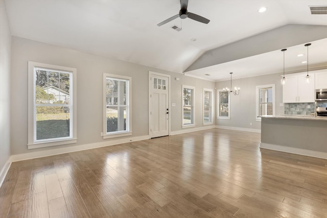 unfurnished living room featuring light hardwood / wood-style flooring, ceiling fan with notable chandelier, and vaulted ceiling