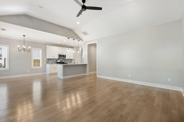 unfurnished living room featuring ceiling fan with notable chandelier, light wood-type flooring, and lofted ceiling