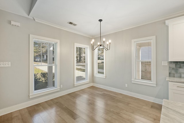 unfurnished dining area with plenty of natural light, light hardwood / wood-style flooring, a chandelier, and ornamental molding