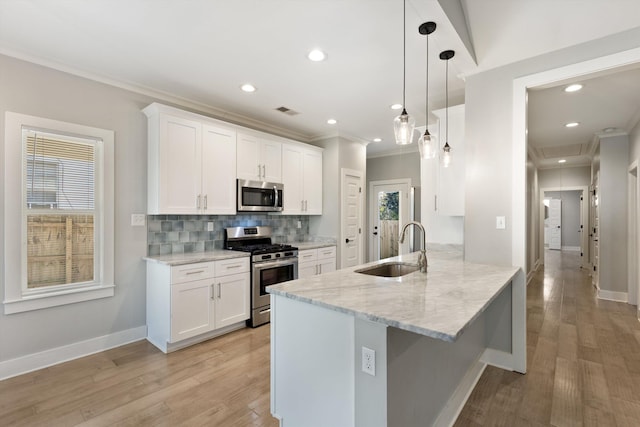 kitchen featuring kitchen peninsula, stainless steel appliances, sink, pendant lighting, and white cabinetry