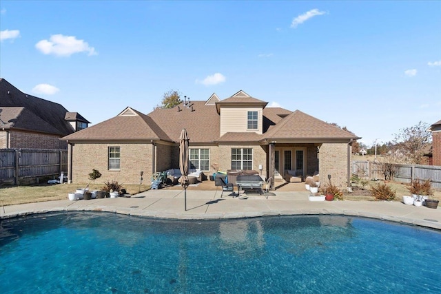 rear view of property featuring a patio area and a fenced in pool