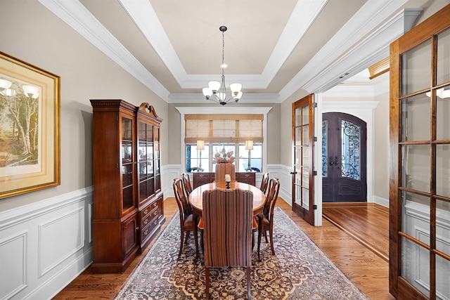 dining space with ornamental molding, dark wood-type flooring, a tray ceiling, and french doors