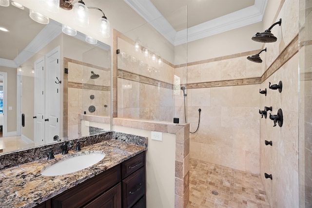 bathroom with vanity, ornamental molding, and tiled shower