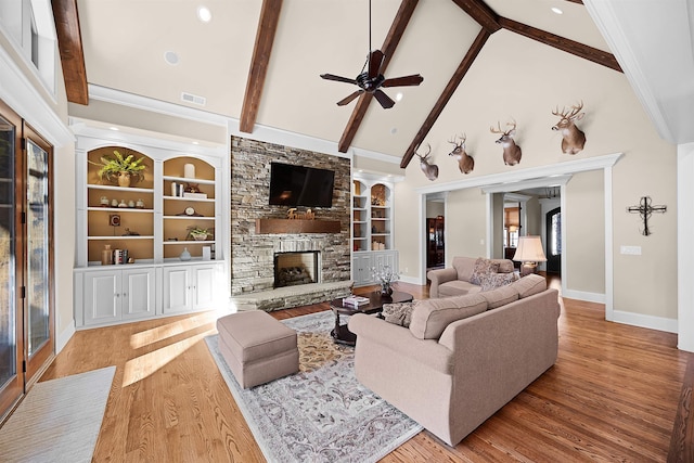 living room featuring beam ceiling, built in features, high vaulted ceiling, light hardwood / wood-style floors, and a fireplace