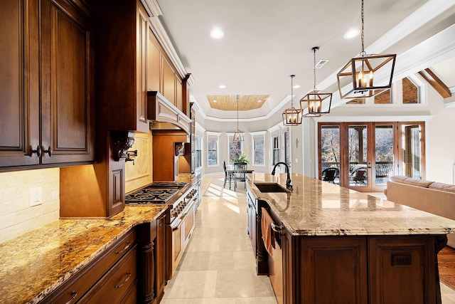 kitchen with decorative backsplash, french doors, sink, a large island with sink, and hanging light fixtures