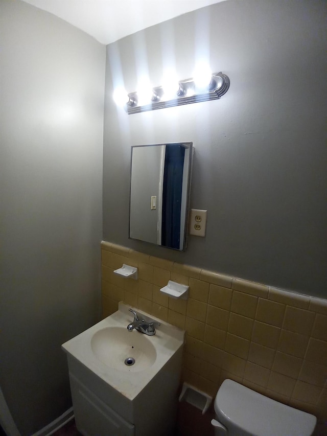 bathroom with toilet, sink, and tile walls