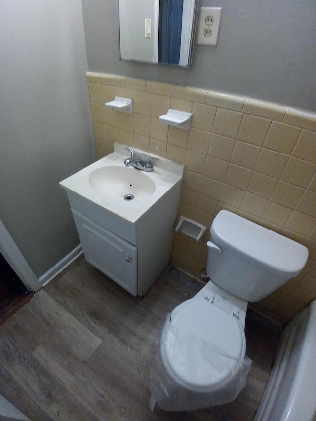 bathroom with toilet, vanity, tile walls, and hardwood / wood-style flooring