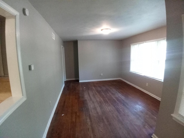 unfurnished room with dark wood-type flooring