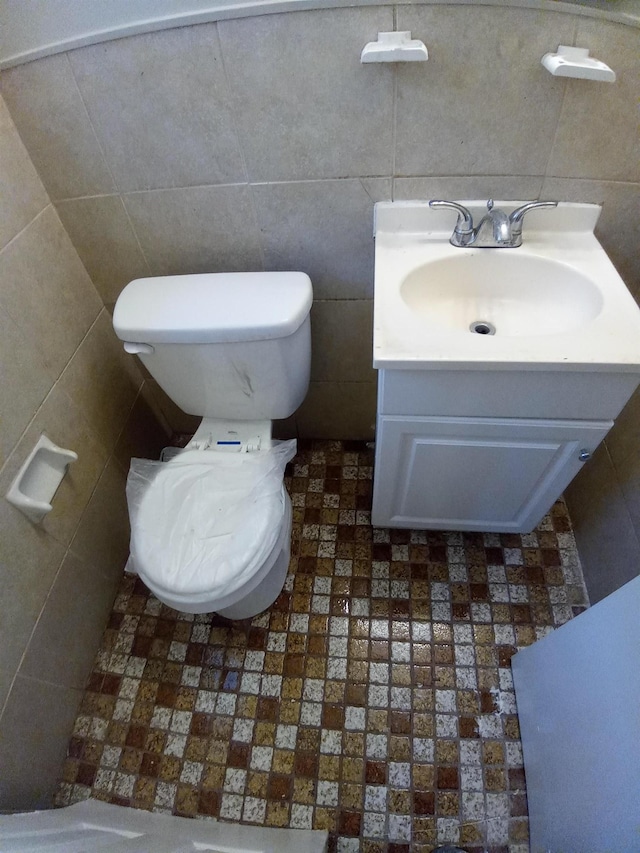 bathroom featuring vanity, toilet, and tile walls