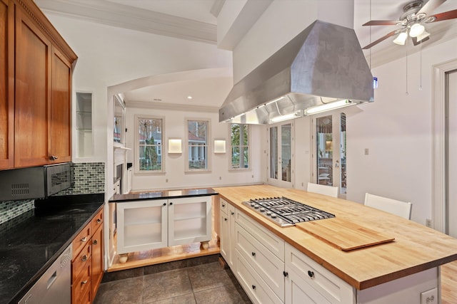 kitchen with butcher block counters, tasteful backsplash, crown molding, island range hood, and white cabinets