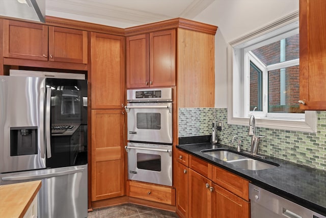 kitchen featuring backsplash, stainless steel appliances, crown molding, sink, and dark stone countertops