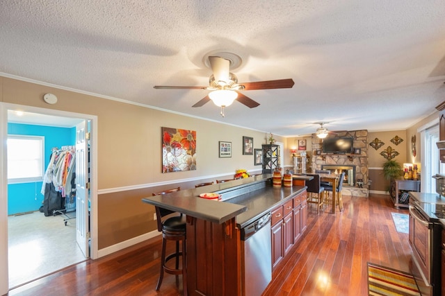 kitchen featuring dishwasher, dark hardwood / wood-style floors, a textured ceiling, a fireplace, and a breakfast bar